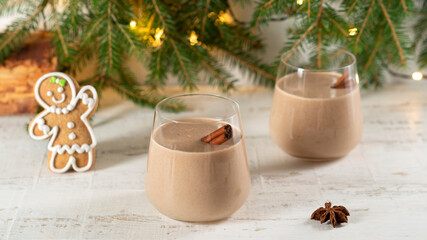 A glass of eggnog traditional winter drink with ground cinnamon. Gingerbread man