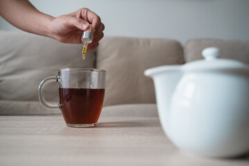 Cannabis hemp oil - Woman adding drop of cbd in tea cup with pipette - Dietary supplements and vitamins concept