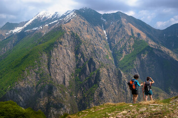 Fototapeta na wymiar Girls hikers with backpack and trekking poles walk along a path in a panoramic point of the Val Grande National Park, Europe, Piedmont Italy.