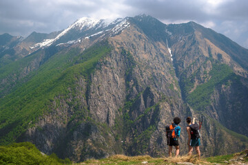 Fototapeta na wymiar Girls hikers with backpack pointed the mountains to spot the local fauna on top of a panoramic point, the Val Grande National Park, Europe, Piedmont Italy.