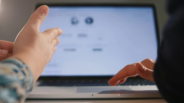 Hands of office workers gesticulate in a discussion using a laptop. Communication using gestures. Bokeh monitor motion picture background.