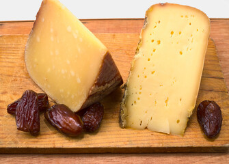 Dos trozos de queso francés y dátiles sobre una tabla de madera