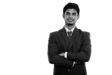 Studio shot of young happy Indian businessman smiling with arms crossed