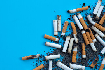 Cigarettes buds with ashtray on blue background.