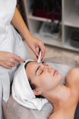 Fototapeta na wymiar Woman client in salon receiving manual facial massage from beautician