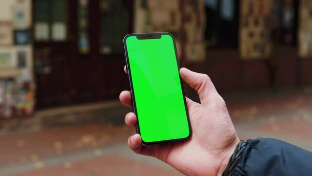 Shot hands man using phone with vertical green screen background on street terace city blurred internet chrome outdoor. Cellphone media device. Slow motion