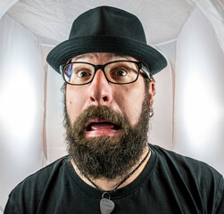 A bearded and silly looking man with black glasses and hat
