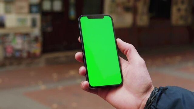 Close up hands man using phone with vertical green screen background on street terace city blurred internet chrome outdoor. Cellphone media device. Slow motion