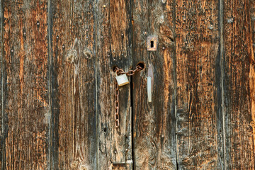 Old wooden door with chain and security lock