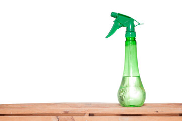 green sprayer with liquid inside on wooden table and white background to help against coronavirus