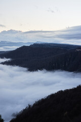 Low clouds, view of winter forest and mountains from observation deck, vertical picture of amazing...