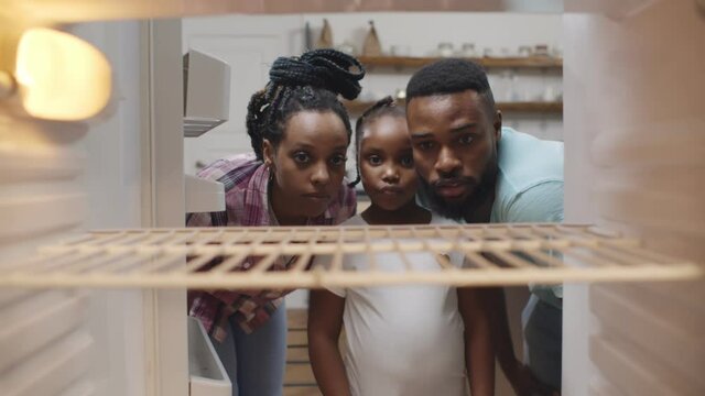 Afro-american hungry family looking into empty fridge at home