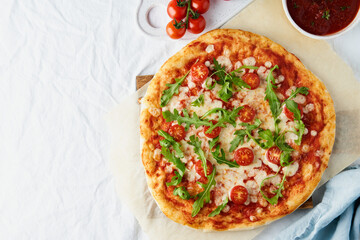 Rustic Italian homemade Pizza Dough margherita topped with pizza sauce from canned tomatoes, mozzarella cheese and arugula, top view, copy space
