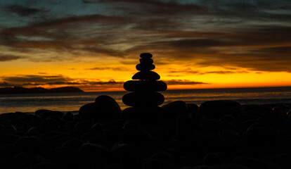 The sun rising over the Atlantic ocean on the east coast of Canada. Silhouette of a pile of stacked rocks.