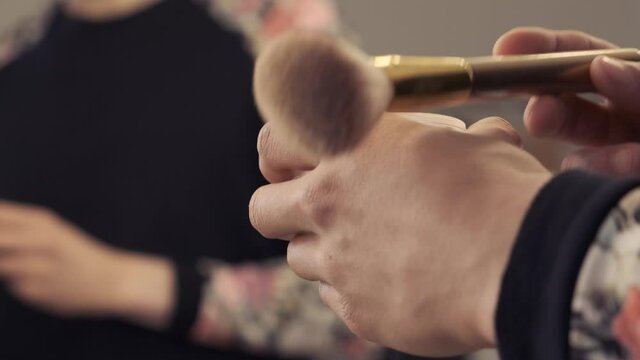 Close-up shot. Androgynous man takes a brush to apply powder. Gender identity concept 4k