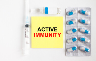 Yellow sticker with text Active Immunity on a white background with syringes, pills and ampoule.