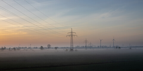 Fototapeta na wymiar misty morning in an agricultural landscape with wind turbines, rural, idyllic, renewable energy