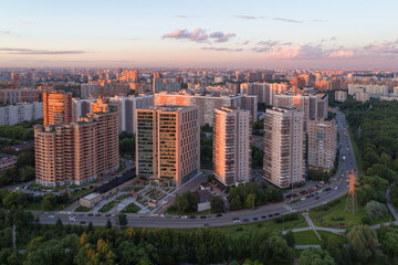 A great metropolis at sunset in the summer. View from the height of a part of the park and the street with large modern houses