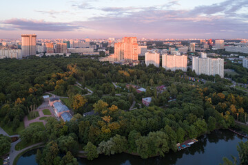 Obraz premium A great metropolis at sunset in the summer. View from the height of a part of the park and the street with large modern houses