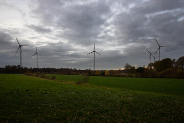 Fototapeta na wymiar wind farm with agricultural field in the foreground and moody clouds in the background