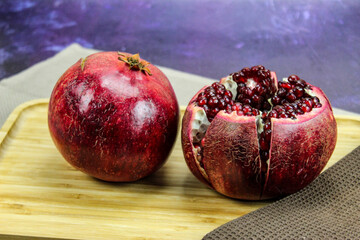 Two large large red pomegranate fruits. Whole red ripe pomegranate. Pomegranate fruit open which is...