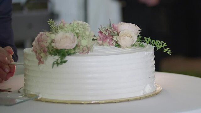 A bride and a groom is cutting their beautiful floral wedding cake during reception party
