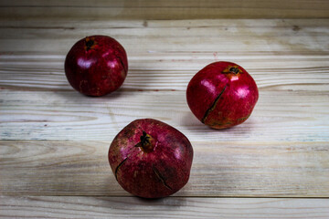 Three ripe pomegranate fruits. Pomegranates on wooden planks backgrounds. Red large pomegranates.