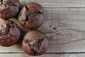 Top view of homemade freshly baked chocolate muffins, keks or cupcakes on wooden table with place for text. Bakery, bakery, bakery.