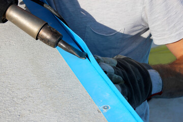 A worker welds plastic cover for water pool. Water pool cover replacement. Plastic Welding Machine....