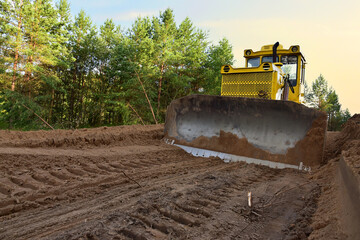 Dozer during clearing forest for construction new road . Yellow Bulldozer at forestry work Earth-moving equipment at road work, land clearing, grading, pool excavation, utility trenching - obrazy, fototapety, plakaty