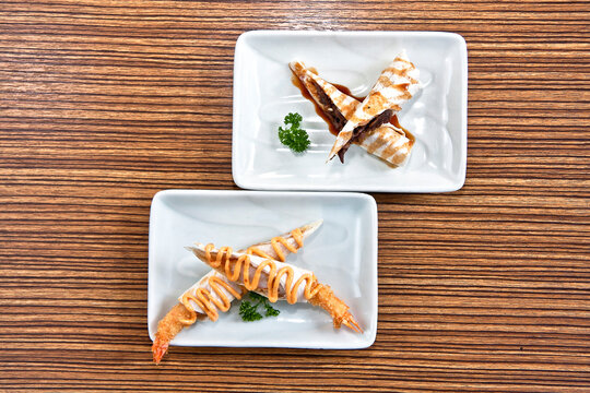 Shrimp Tacos With Chipotle Chili Dressing And Rib Eye Tacos With Burrito Style Tamarind Sauce On A Square White Plate Over Wood Background, Overhead View