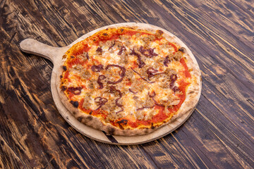 Tuna and onion pizza on dark wooden background