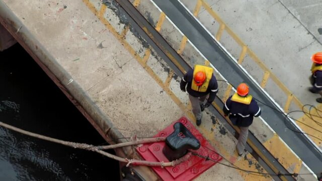 Port Workers pulling a Mooring Rope of a large Container Ship. 