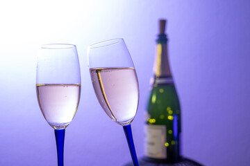 Sektgläser vor farbigem Hintergrund mit Champagnerflasche