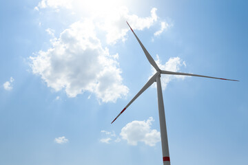 Modern wind turbine against blue sky, low angle view. Energy efficiency