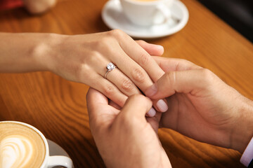 Fototapeta na wymiar Man with engagement ring making proposal to his girlfriend in cafe, closeup