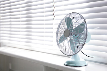 Modern electric fan on window sill indoors. Space for text