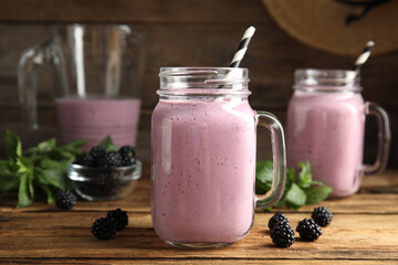 Tasty milk shake with blackberries on wooden table