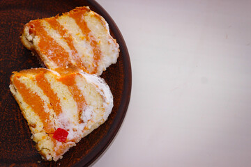 Two pieces of pumpkin cheesecake standing on a clay plate on a white background