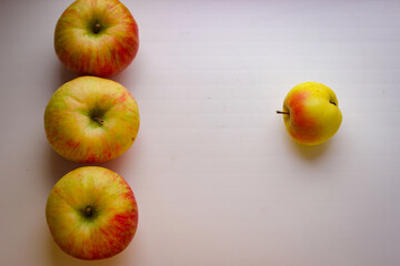 A few ripe apples on a white surface. Rear background is blurred