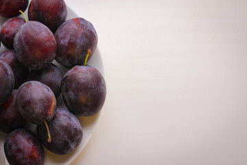 Appetizing ripe plums on a white background with copy space