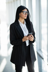 Young smiling business woman using smartphone in office