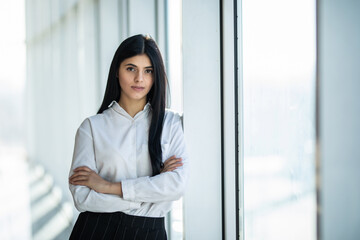 Young businesswoman crossed hands portrait in office with panormic windows.