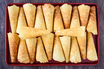 Norwegian Krumkake cookies on a red tray on a rustic dark wood table
