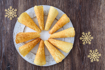 Norwegian Krumkake cookies on a white snowflake platter on a rustic wood background
