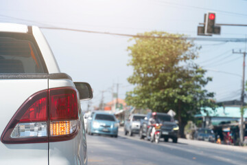 Luxury rear corner of pickup white car on the road. Stop by red traffic signal at the intersection....