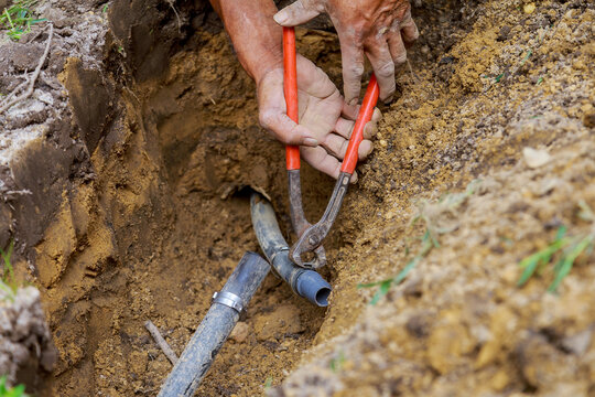 Man working with pipes in ground while Installing a New underground sprinkler system