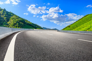 Asphalt road and mountain with tea plantation under blue sky.Road and mountain background.