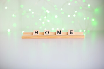 the word home spelled out in scrabble tiles against a white background and fairy lights