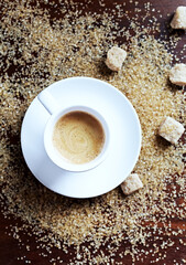 Cup of coffee and brown sugar on wooden background. Top view.